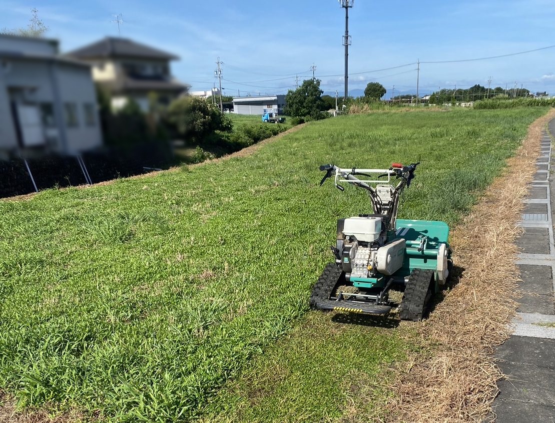 ハンマーナイフモアで広い土地を草刈りしている現場